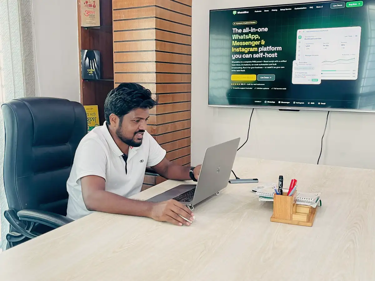 Abdul Mannan Zinnat working on a laptop with the WhatsAble site on a wall screen